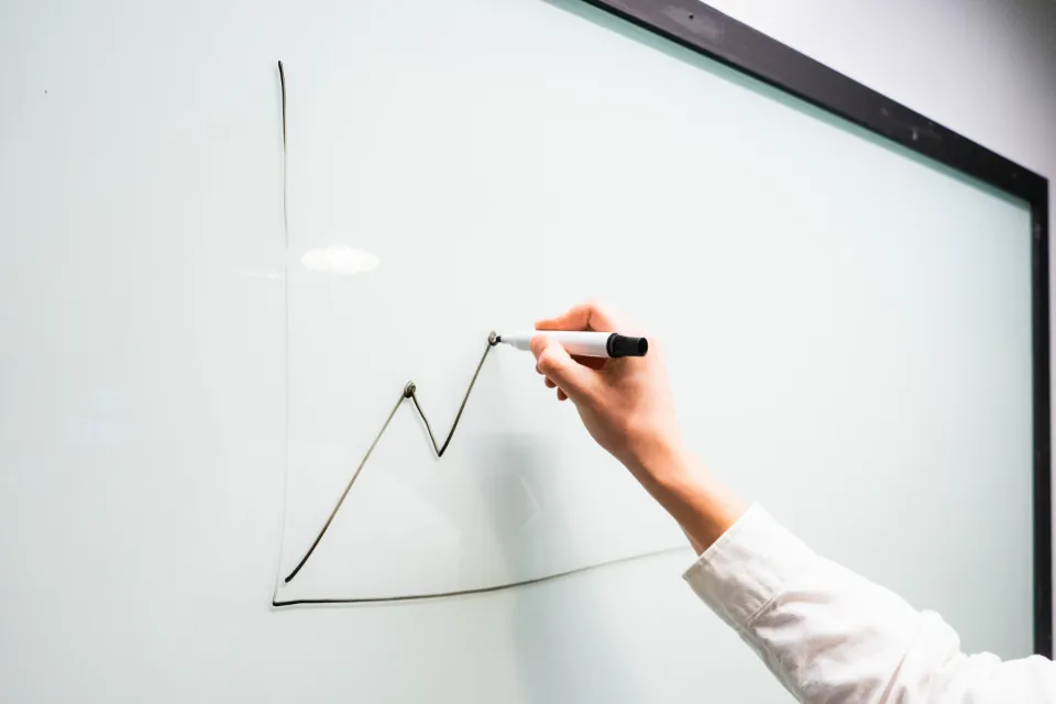 Estrategia de crecimiento: mano dibujando en una pizarra blanca una curva de crecimiento ascendente
