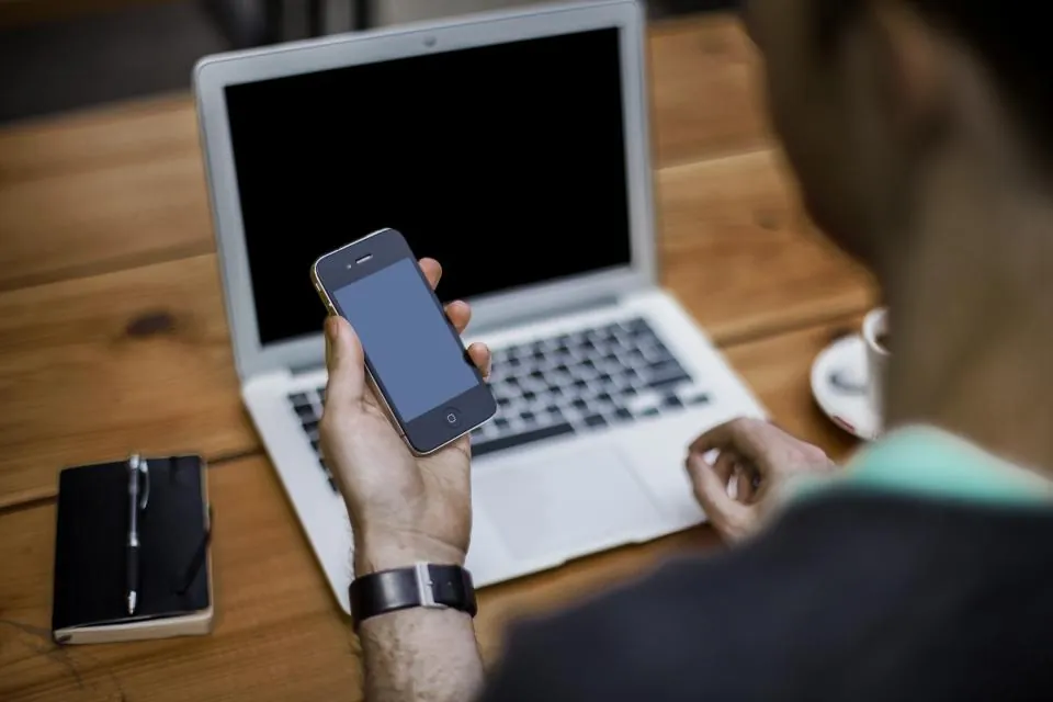 Mobiltilpasset webdesign: nettside på en smarttelefon ved siden av en bærbar PC